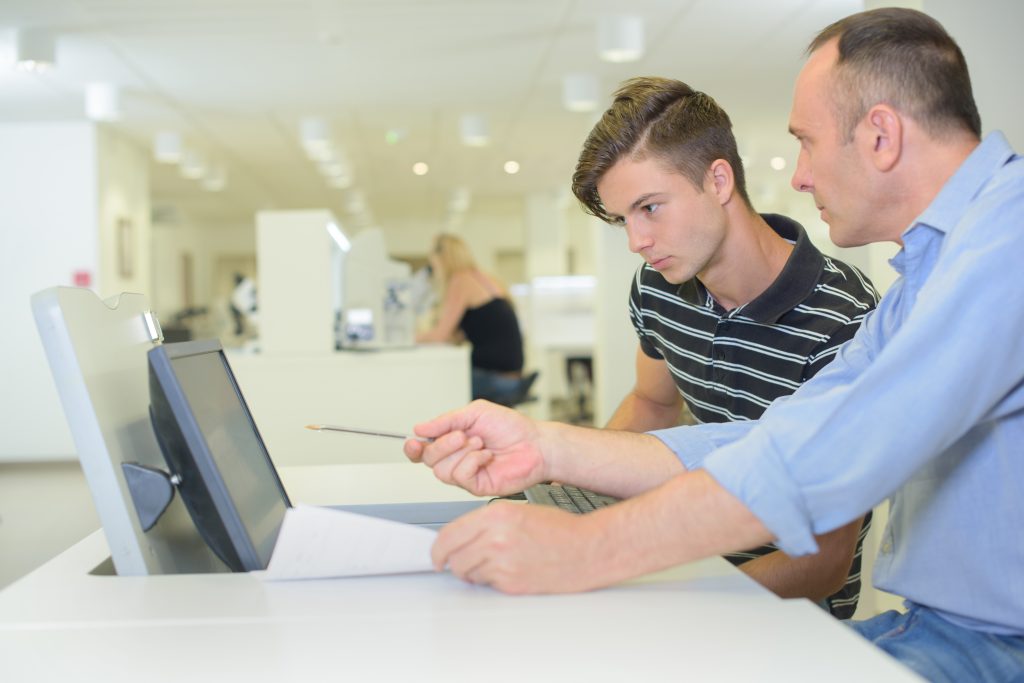 Jovem aprendiz em computador com funcionário