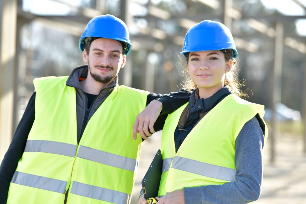 Dois jovens com roupas de trabalhadores e equipamentos de segurança.