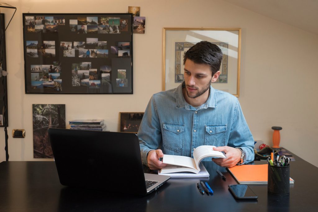 Homem estudando com computador e livro