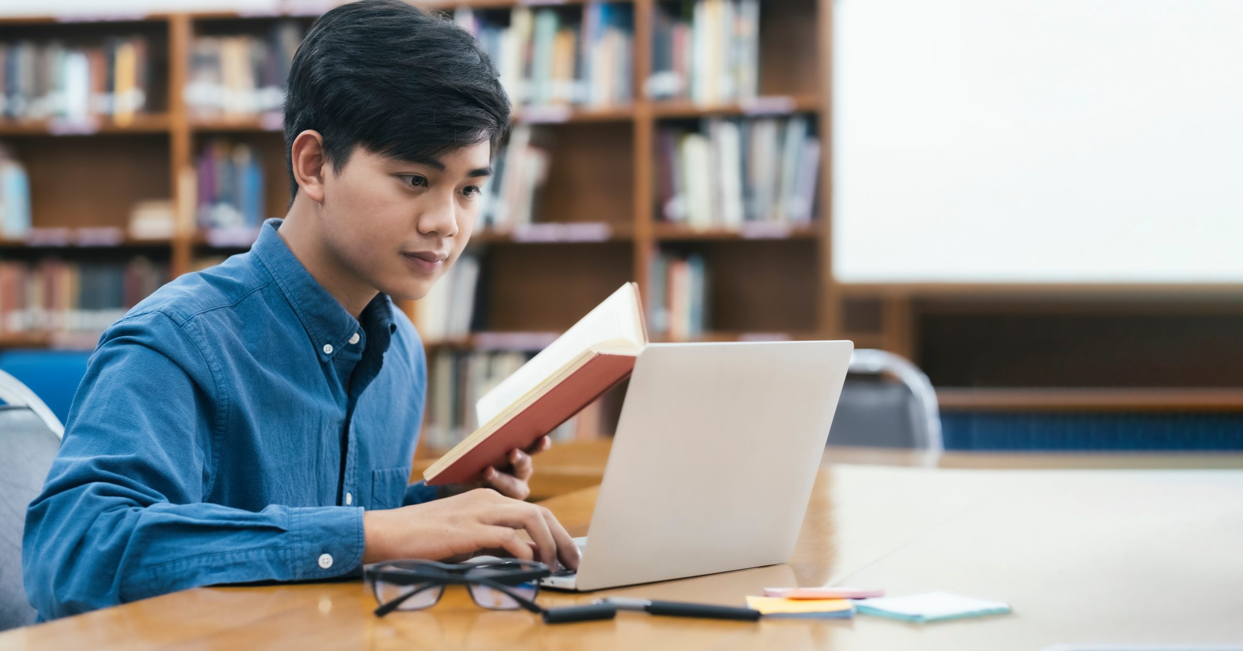 Homem estudando com livro e computador