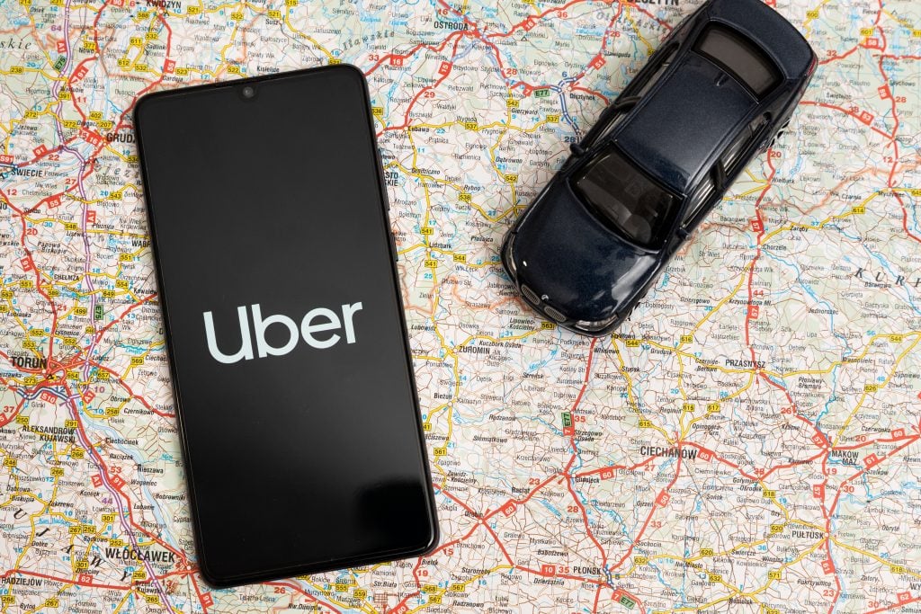 Celular com app Uber aberto em cima de um mapa.