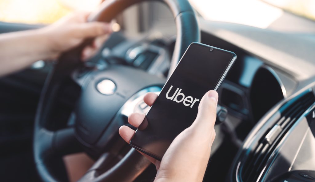 Motorista segurando um celular exibindo tela do Uber