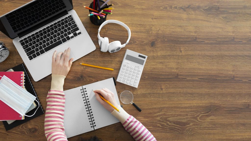 computador e caderno em mesa de estudos