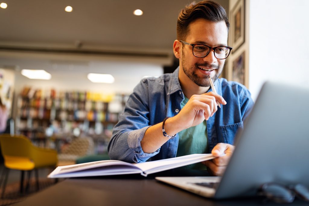 Homem estudando com computador e livro