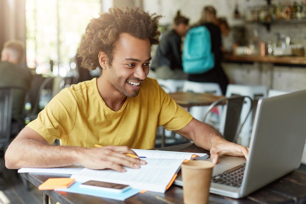 Homem estuda com computador e livro