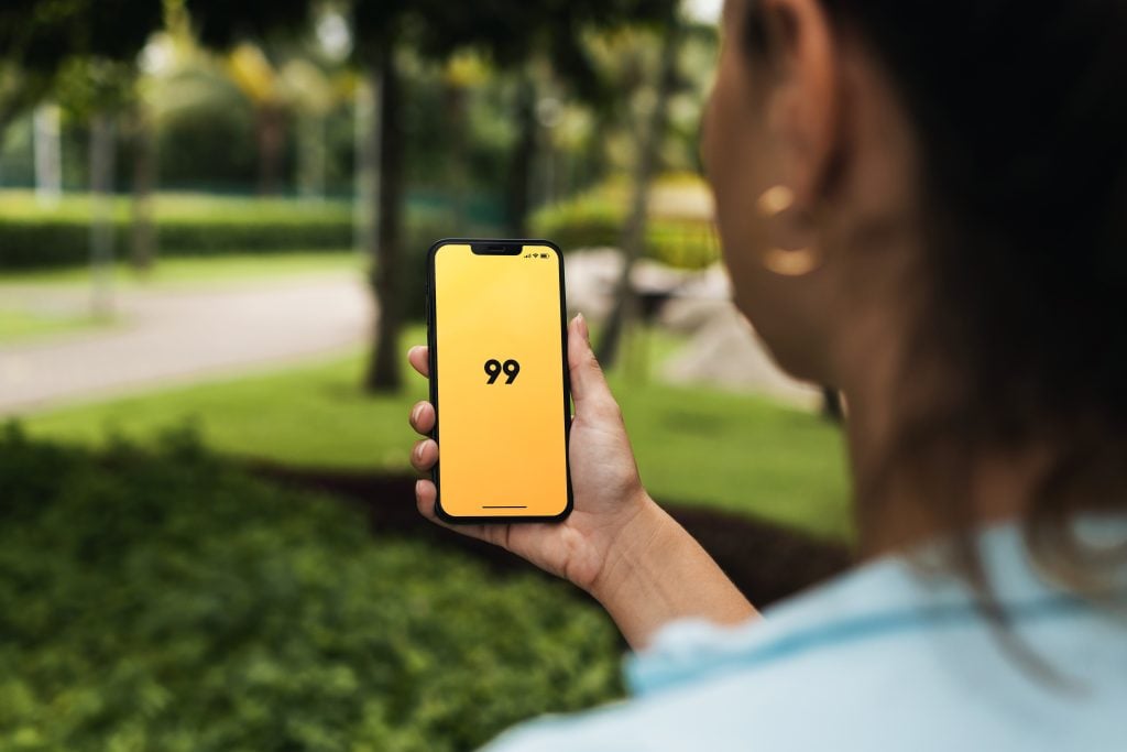 Mulher segurando um celular com o logo da 99