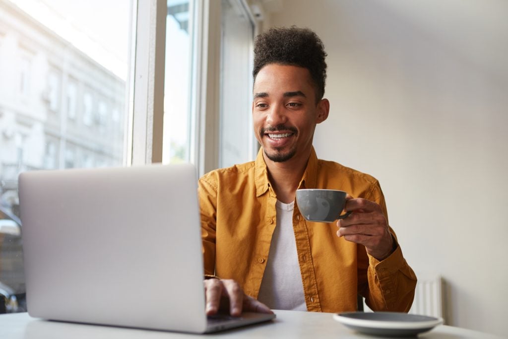 Homem trabalha no computador com uma xícara de café