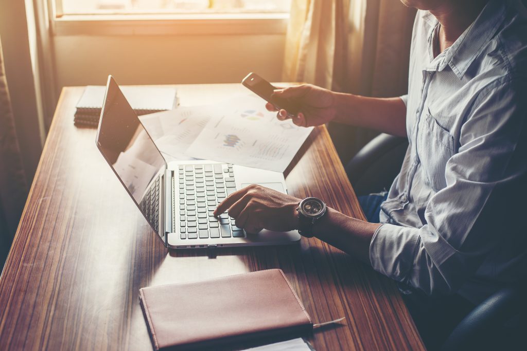 Homem freelancer trabalha com celular e computador