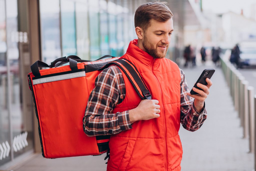 Entregador com bolsa e celular