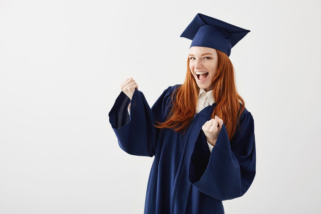 Mulher vestida com beca comemora graduação