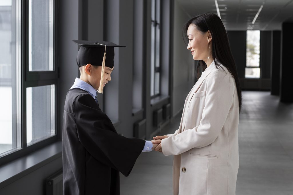 Jovem vestido com beca junto de professora