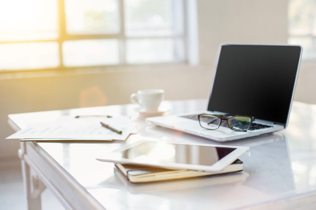 Mesa com papéis, computador, tablet e café