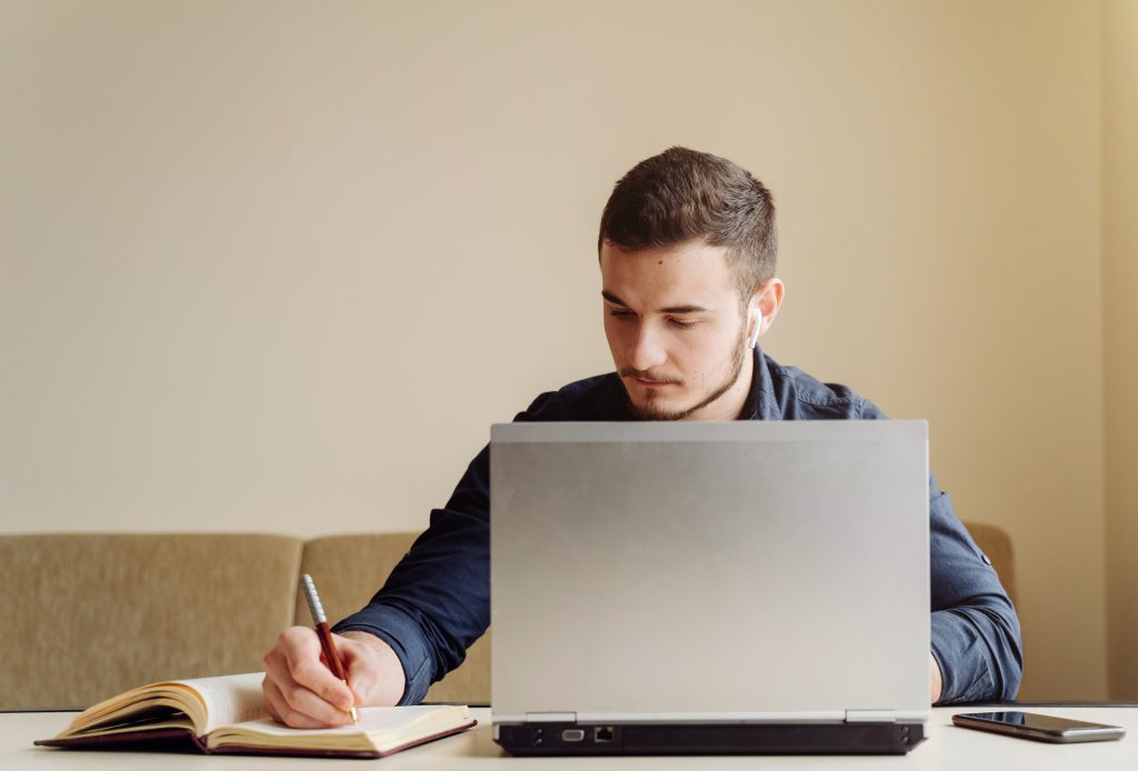 Homem estuda com livro e computador