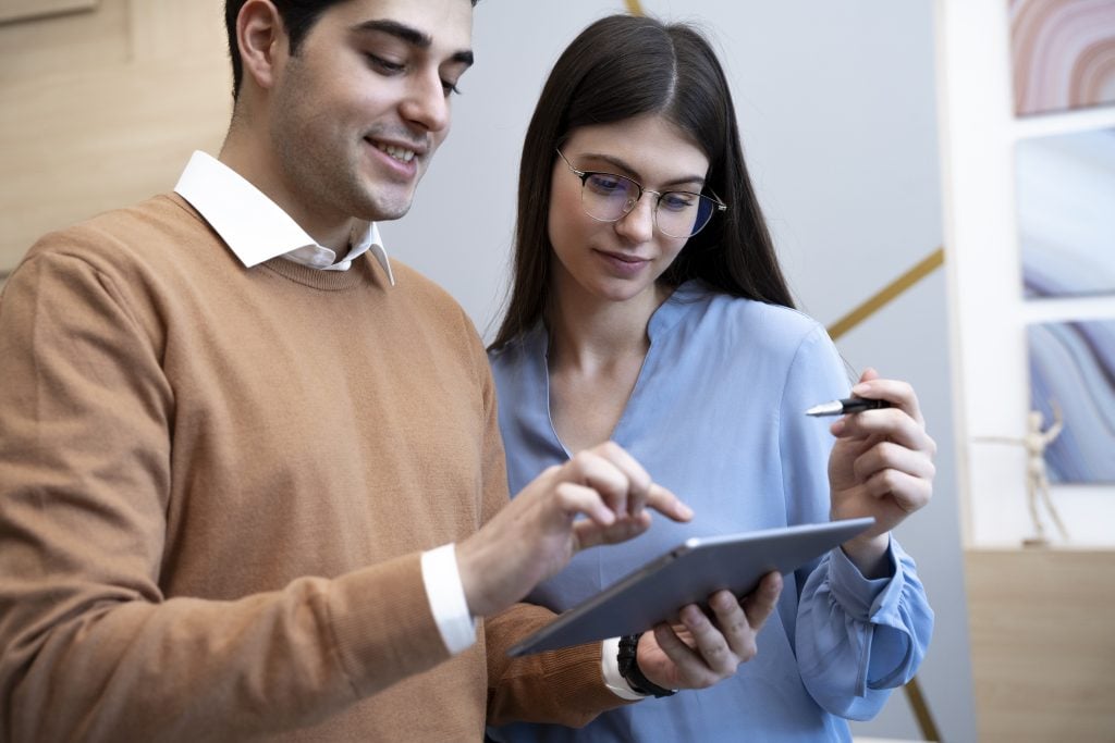 Dois estagiários conversam e usam tablet