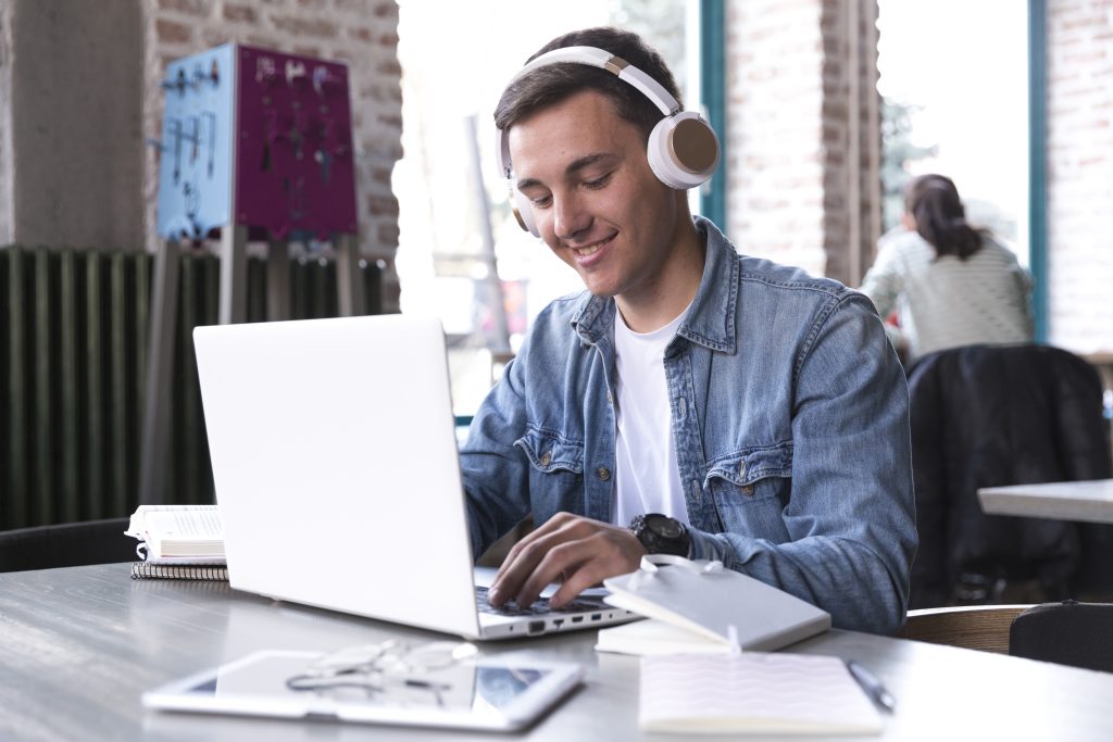 Jovem homem usa computador e fones