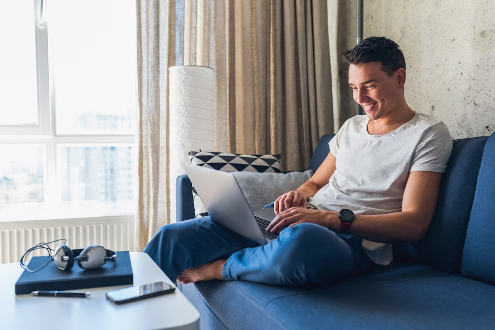 Homem sentado em sofá com notebook